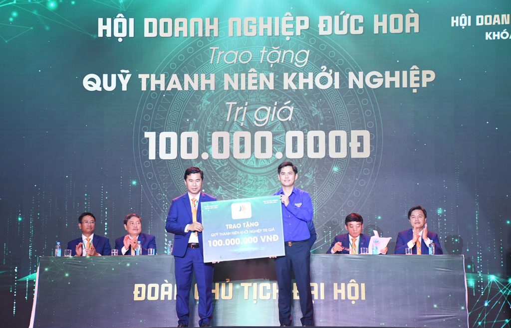 Ông Lê Ngọc Bích (bìa trái) đại diện Ban Chấp hành Hội trao bảng tượng trưng 100 triệu đồng cho Quỹ Khởi nghiệp huyện